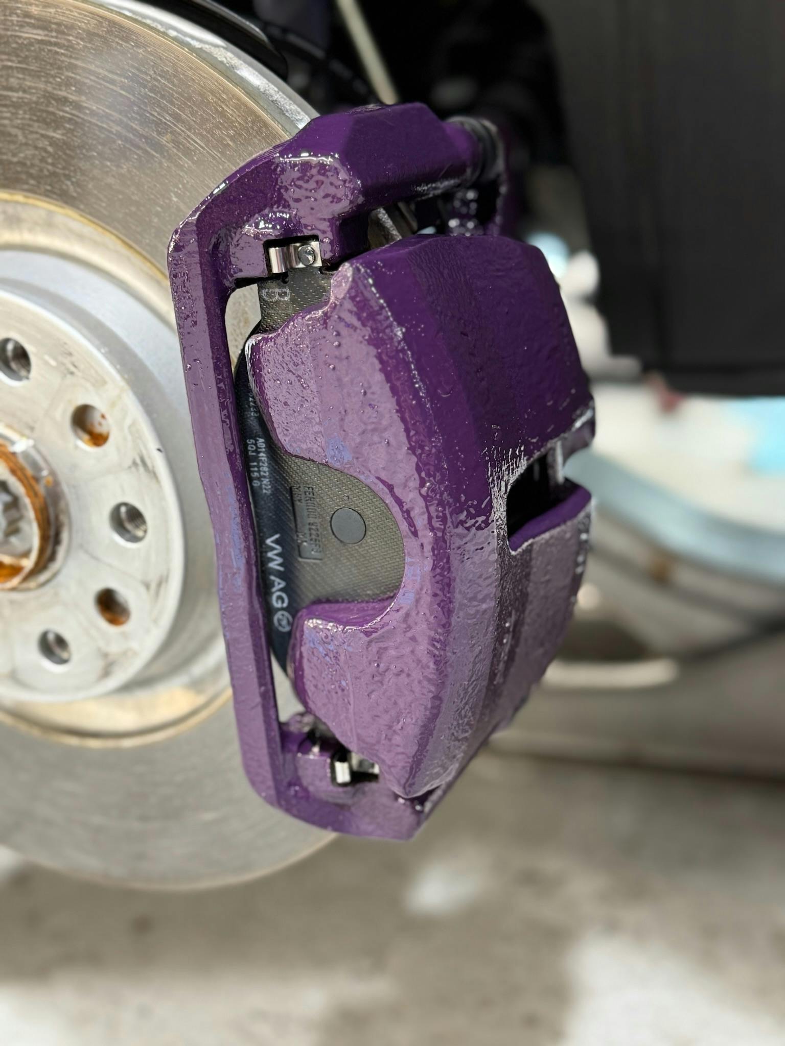 Close-up of freshly painted purple brake caliper with glossy finish
