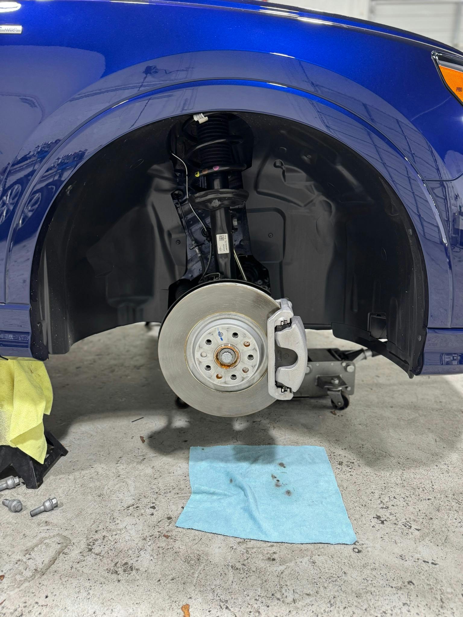 Technician applying high-temperature brake caliper paint in auto detailing shop