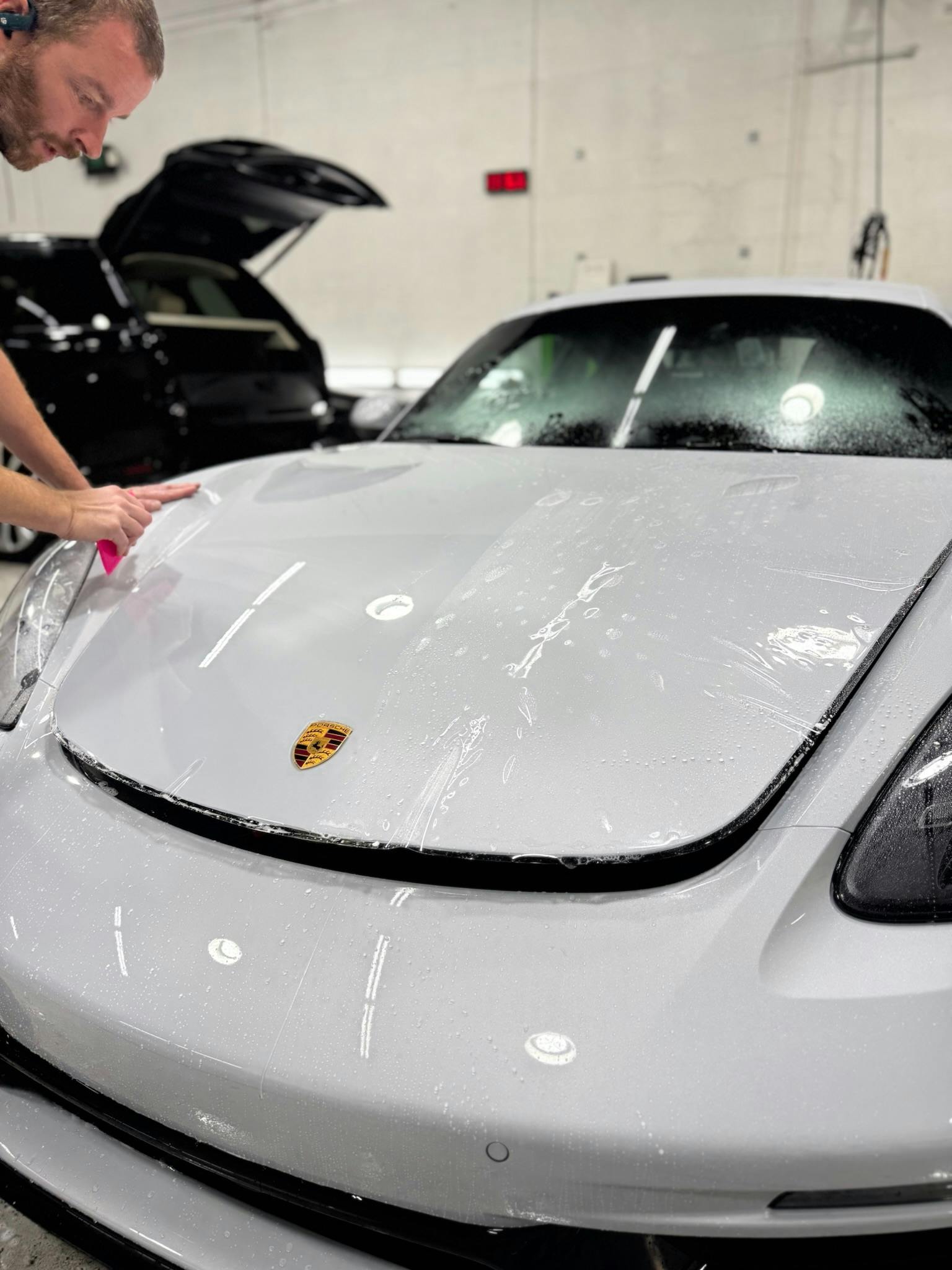Technician applying PPF to a white Porsche hood