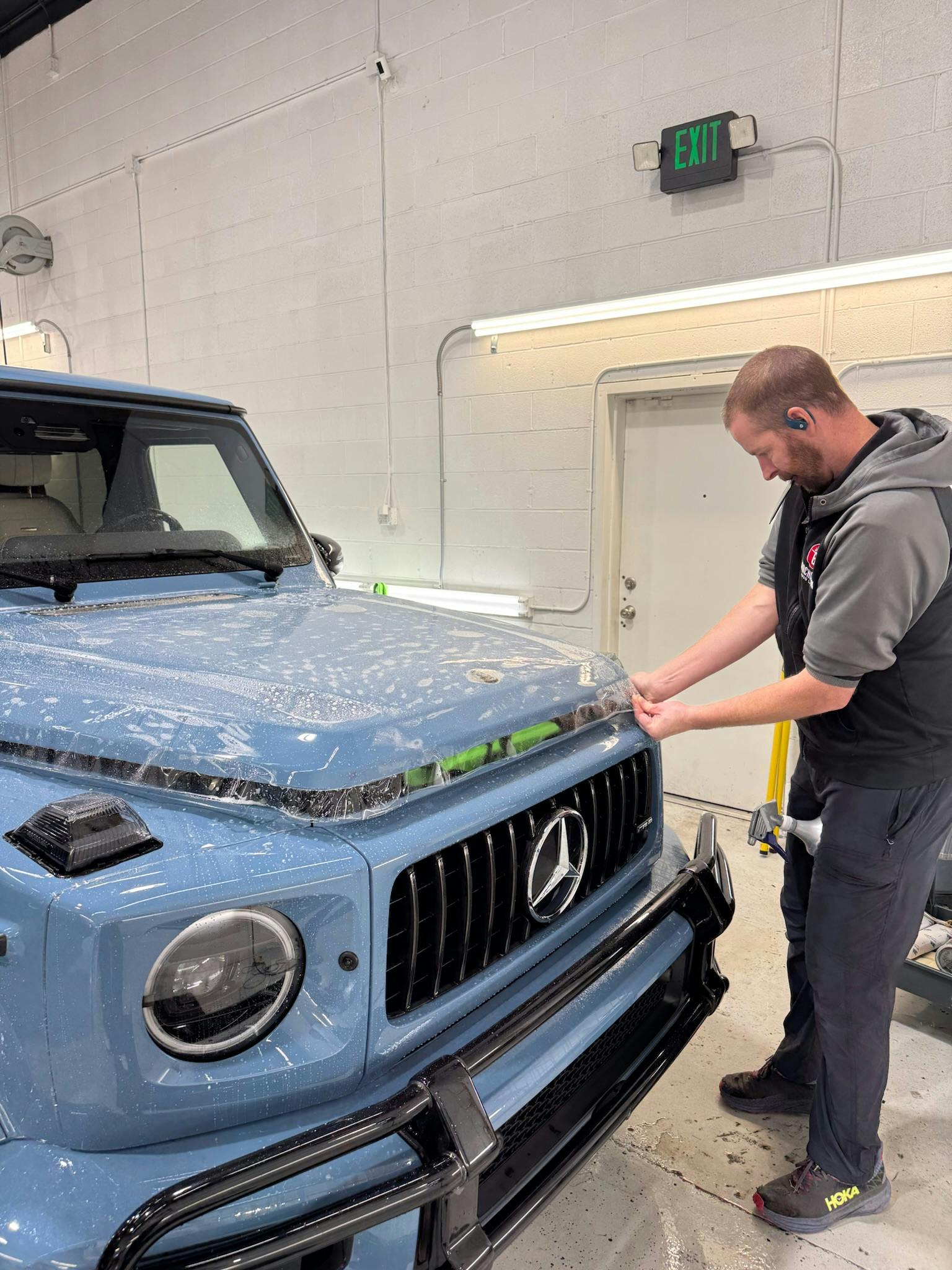 Technician installing PPF on a blue Mercedes G-Wagon