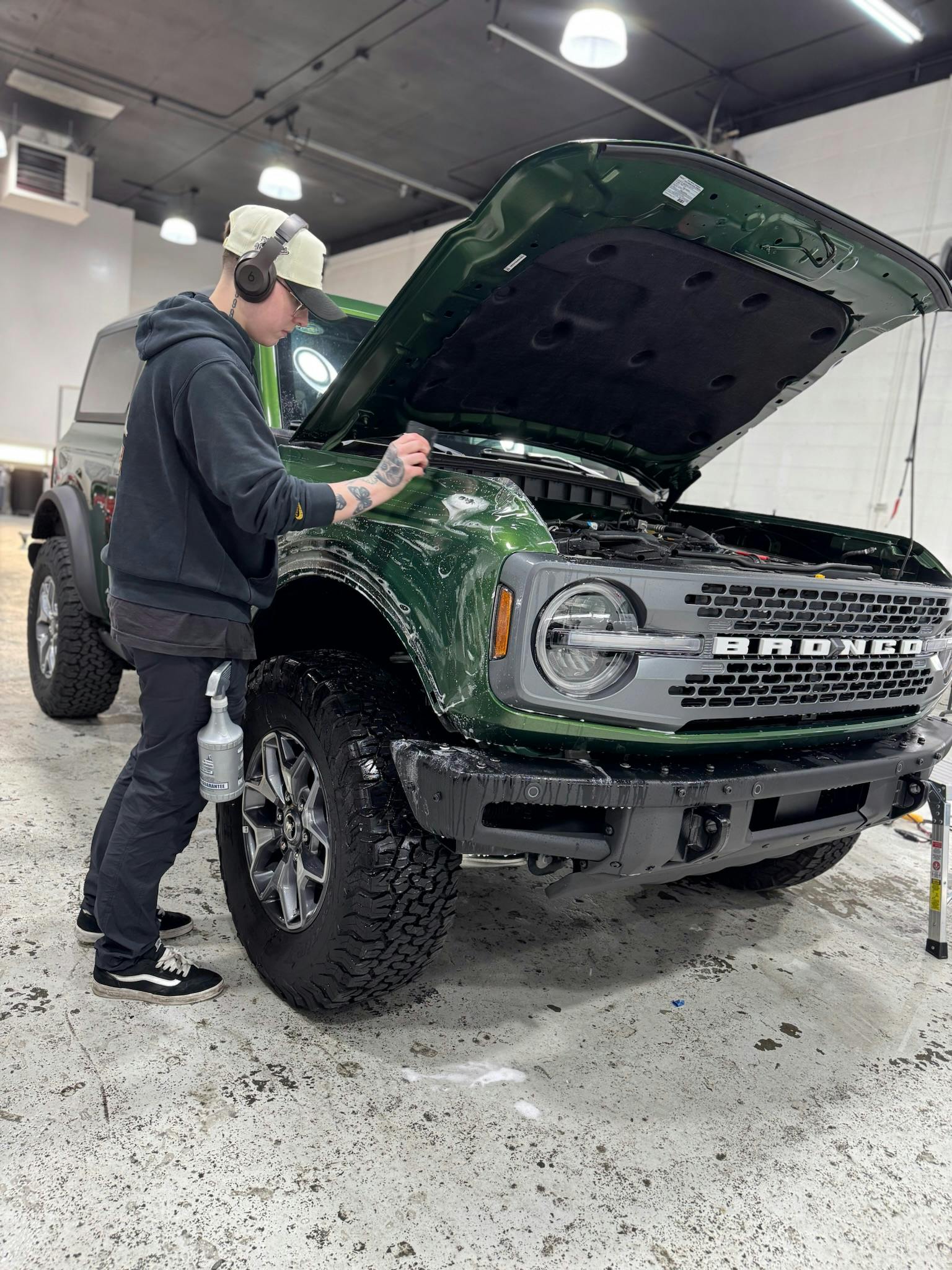 Technician applying paint protection film to a green Ford Bronco