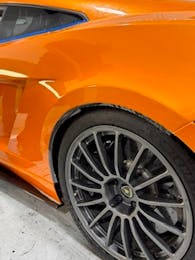 Close-up of orange sports car with paint protection film protecting the rear quarter panel
