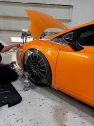 Applying paint protection film to the rear quarter panel of an orange Lamborghini Huracán