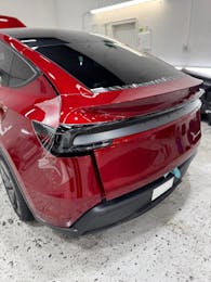 Paint protection film installation on the rear of a red Tesla Model Y
