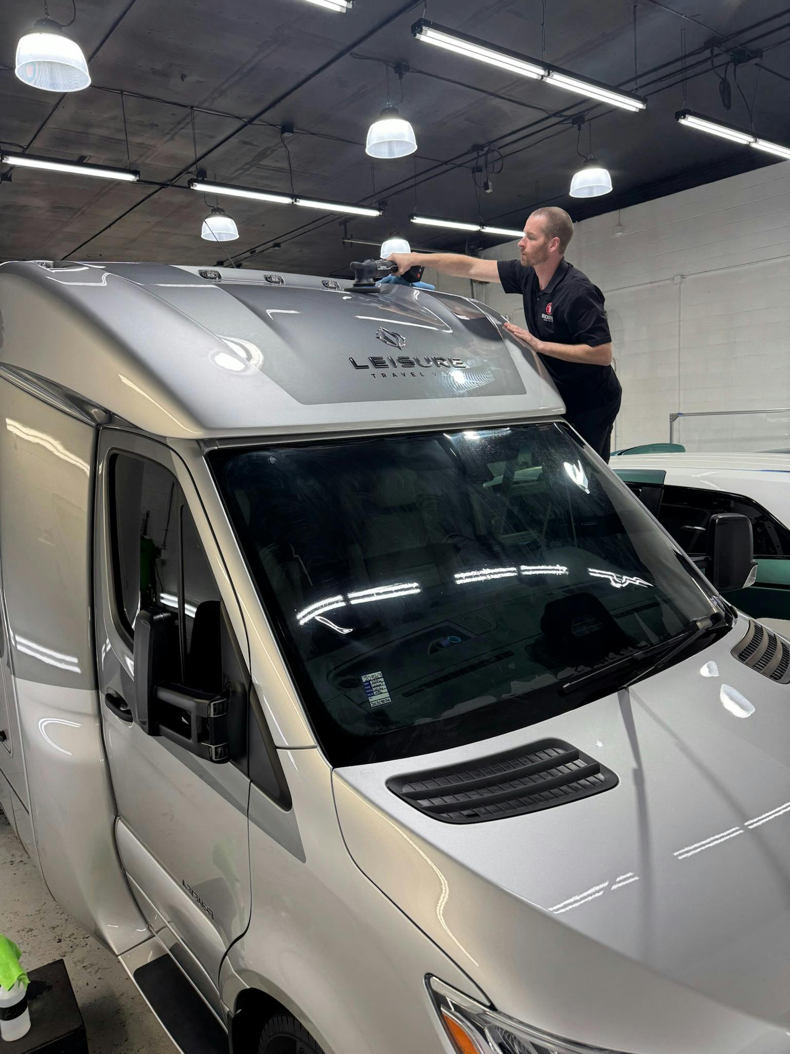 Detailer polishing the front cap and roof of a Leisure Travel Vans Unity motorhome