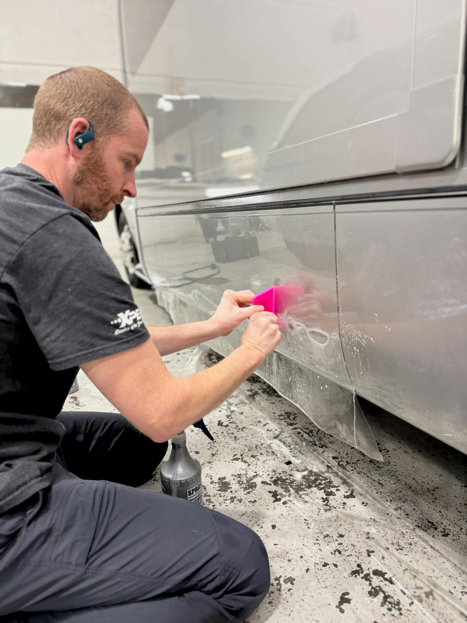 Working a squeegee along the protected lower panel of an RV