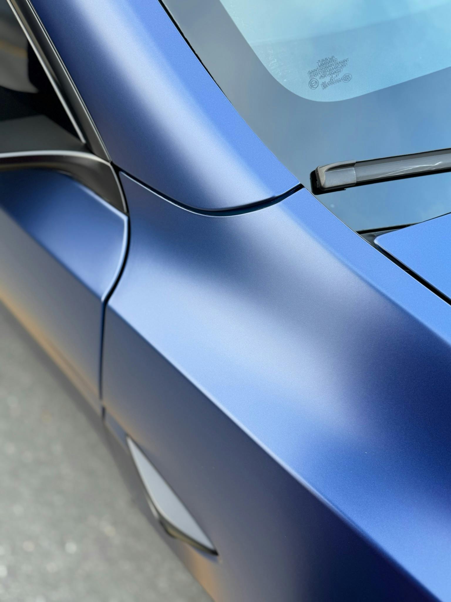 Close-up of XPEL STEALTH satin finish on a blue Tesla door and fender